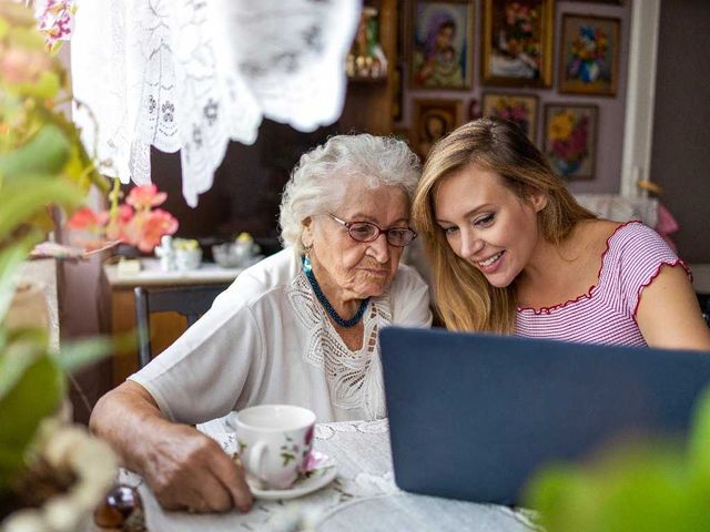 Cuidadora enseñando a persona mayor a usar ordenador