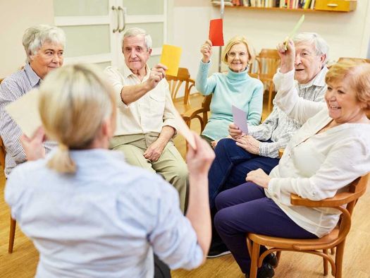 Cuidadora realizando terapia ocupacional a grupo de ancianos